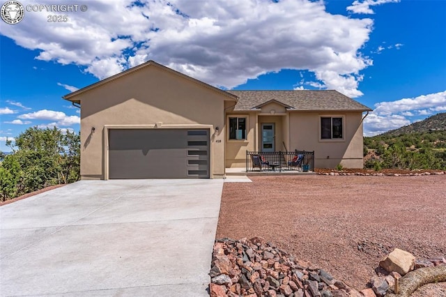 view of front of house with a garage, concrete driveway, and stucco siding