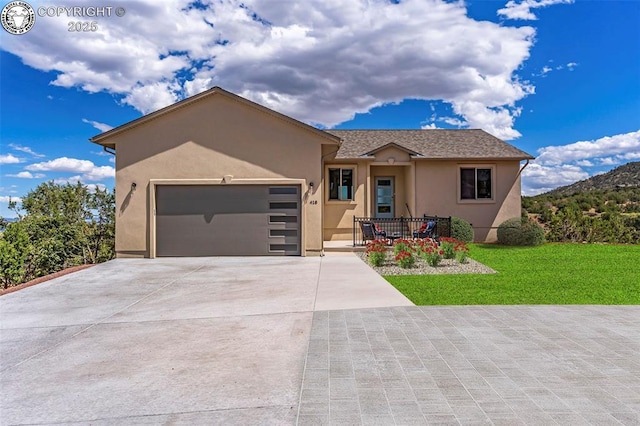 single story home with a garage, driveway, a front yard, and stucco siding