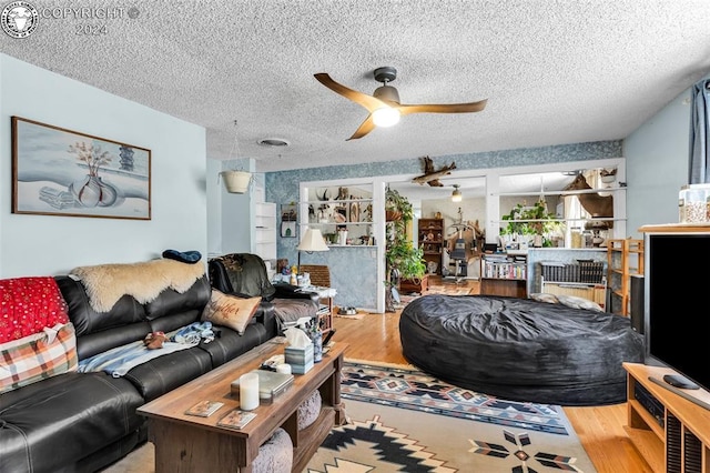 living room featuring wood-type flooring, ceiling fan, and a textured ceiling