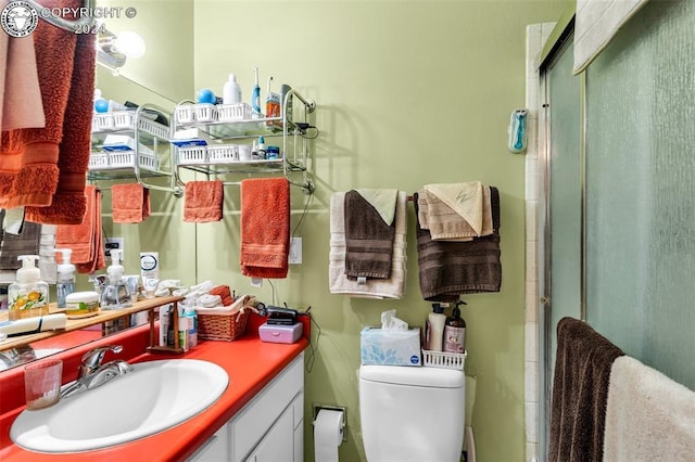 bathroom with vanity, a shower with door, and toilet