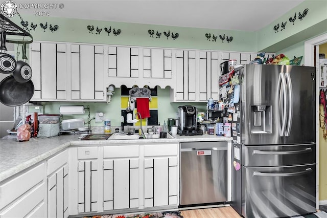 kitchen featuring white cabinetry, appliances with stainless steel finishes, sink, and light hardwood / wood-style flooring