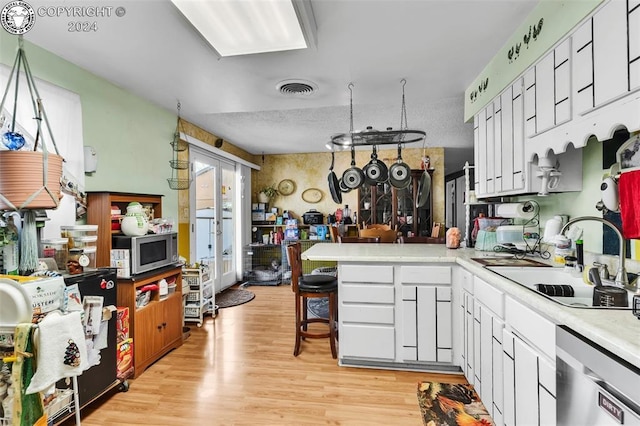 kitchen featuring a breakfast bar, white cabinetry, sink, kitchen peninsula, and stainless steel appliances