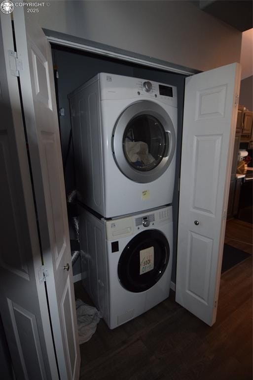 washroom featuring stacked washer / drying machine and dark wood-type flooring