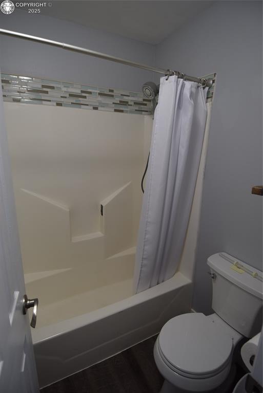 bathroom with shower / tub combo with curtain and toilet