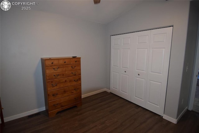 unfurnished bedroom featuring dark hardwood / wood-style floors, vaulted ceiling, a closet, and ceiling fan