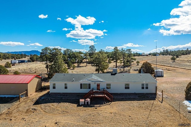 view of front of house featuring a deck with mountain view, a rural view, and a storage unit