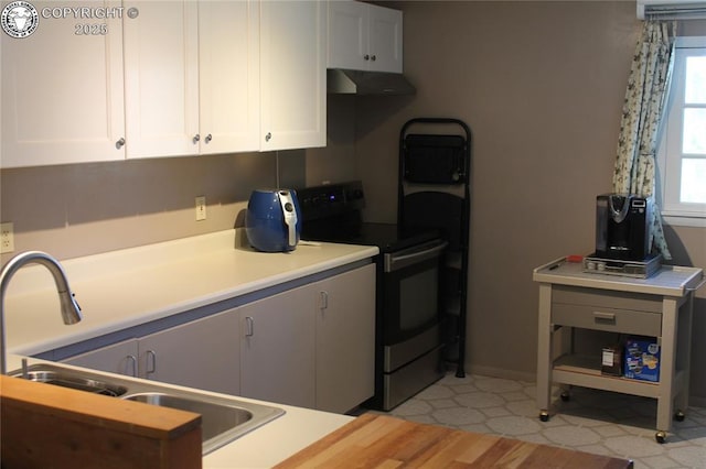 kitchen featuring electric range, range hood, light countertops, white cabinetry, and a sink