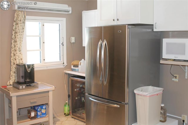 kitchen featuring beverage cooler, white microwave, freestanding refrigerator, light countertops, and white cabinetry