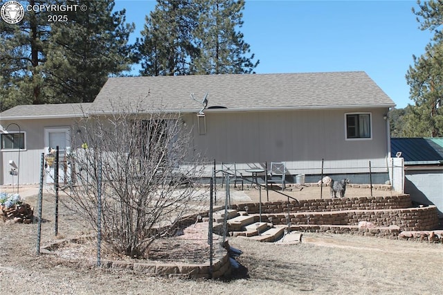 back of property featuring roof with shingles and fence