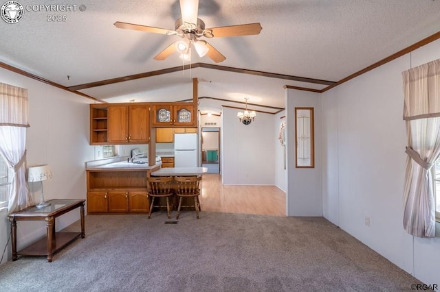 kitchen featuring vaulted ceiling, a breakfast bar area, white fridge, kitchen peninsula, and a textured ceiling