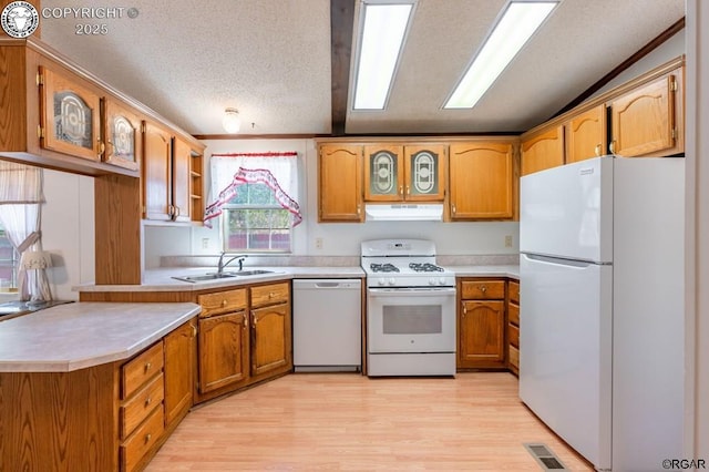 kitchen with sink, white appliances, light hardwood / wood-style flooring, vaulted ceiling, and kitchen peninsula