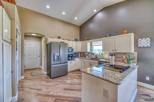 kitchen with sink, light stone counters, stainless steel appliances, decorative backsplash, and white cabinets