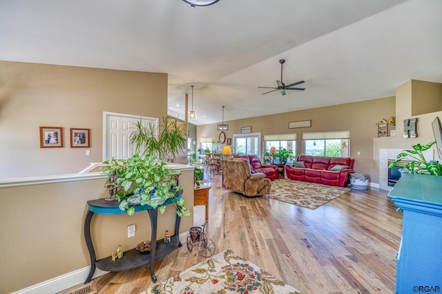 living room with ceiling fan, lofted ceiling, and light wood-type flooring