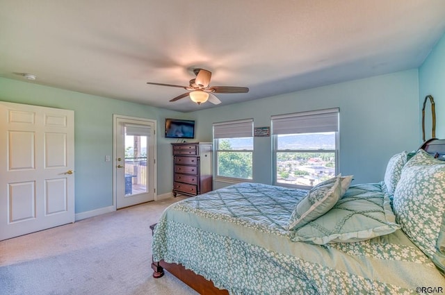 bedroom with ceiling fan, light carpet, multiple windows, and access to outside