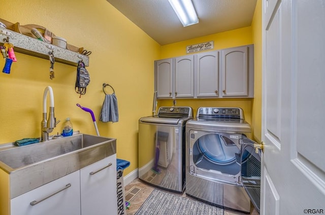 washroom with cabinets, sink, and washing machine and clothes dryer