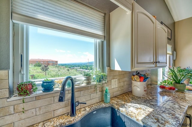 details featuring light stone countertops, sink, and backsplash