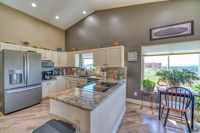 kitchen with appliances with stainless steel finishes, high vaulted ceiling, white cabinets, backsplash, and light stone counters