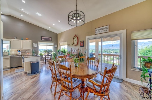 dining room featuring a chandelier, high vaulted ceiling, and light hardwood / wood-style flooring