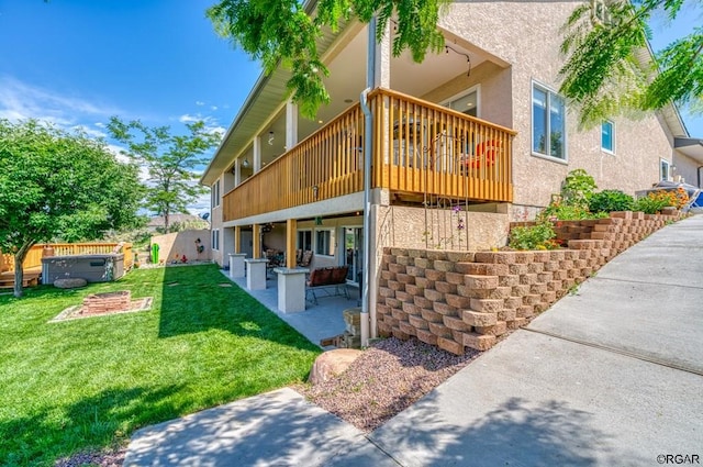 view of property exterior featuring a hot tub, a deck, a patio, and a lawn