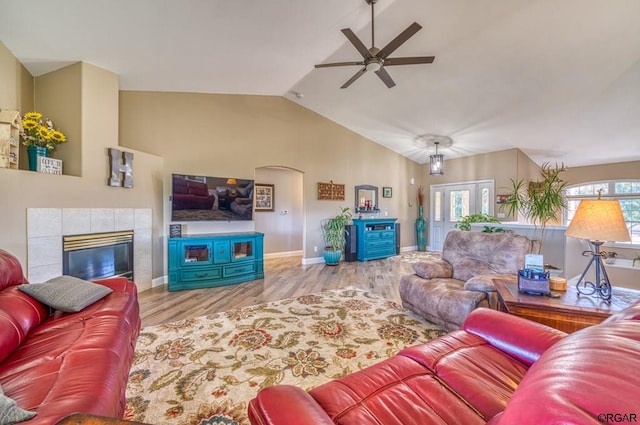 living room with vaulted ceiling, ceiling fan, a fireplace, and light hardwood / wood-style flooring