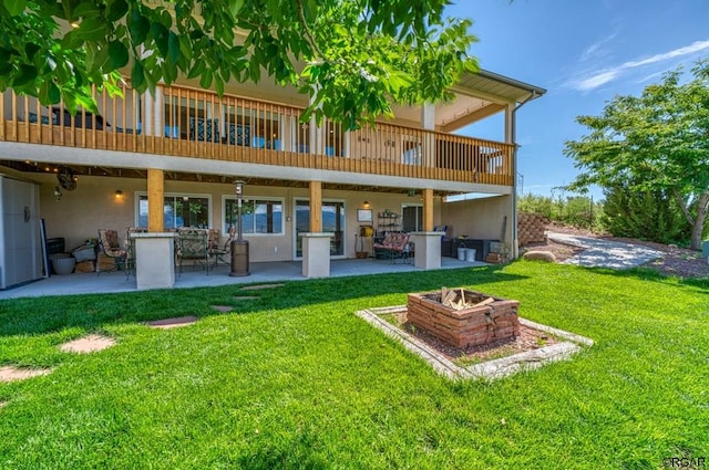 back of house featuring a yard, a patio area, and a fire pit