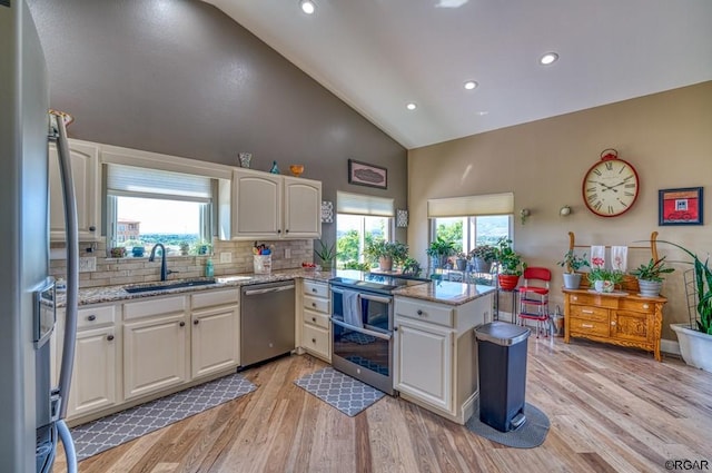 kitchen with sink, light hardwood / wood-style flooring, appliances with stainless steel finishes, white cabinetry, and kitchen peninsula