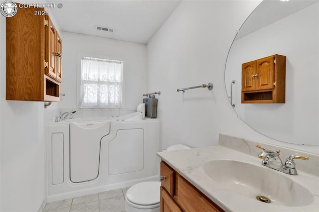 bathroom with vanity, toilet, and a washtub