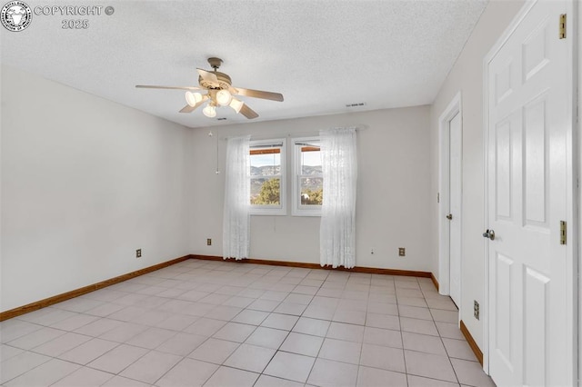 tiled empty room featuring ceiling fan and a textured ceiling