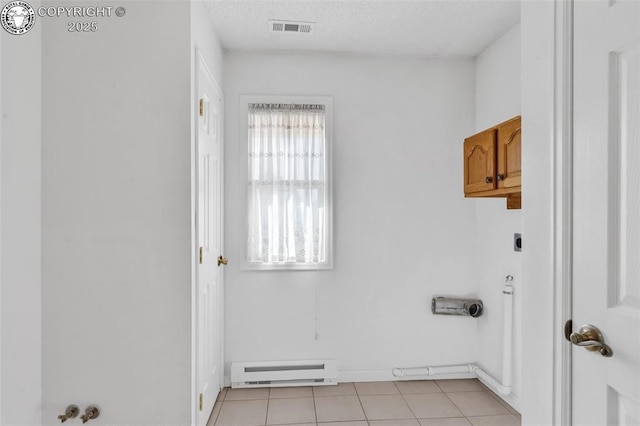 washroom featuring light tile patterned flooring, cabinets, electric dryer hookup, and a baseboard heating unit