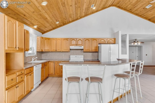 kitchen with light tile patterned flooring, white appliances, a kitchen bar, and a center island