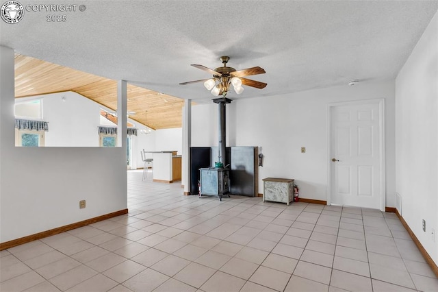 unfurnished living room featuring lofted ceiling, light tile patterned floors, ceiling fan, a textured ceiling, and a wood stove