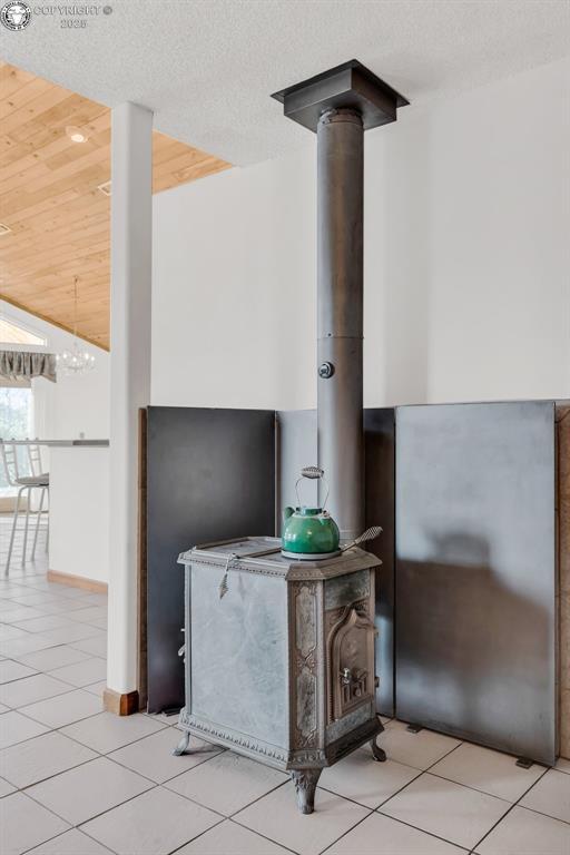 interior details with a wood stove, wooden ceiling, and a textured ceiling