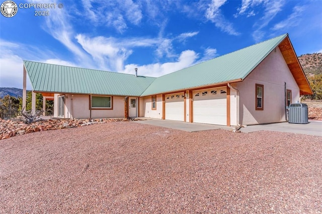 view of front of property with a mountain view, a garage, and central AC