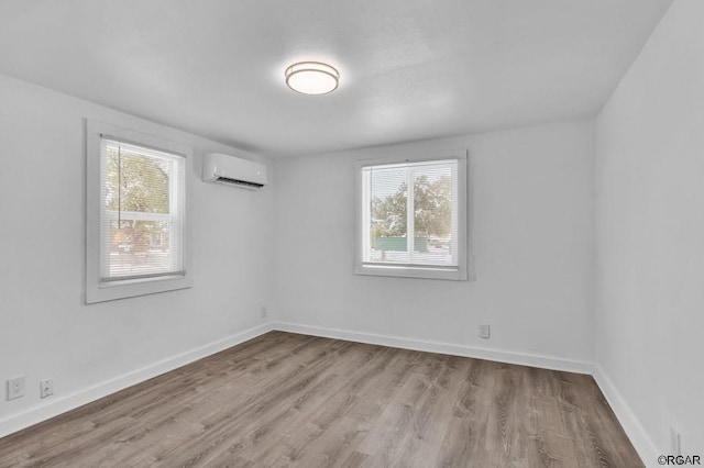 spare room featuring a wall mounted AC and light wood-type flooring