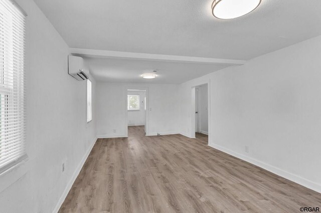 spare room featuring a wall mounted air conditioner and light hardwood / wood-style flooring