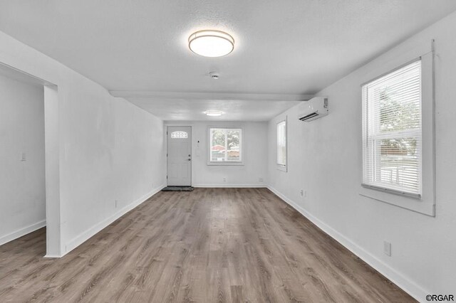 interior space featuring a textured ceiling, light hardwood / wood-style flooring, and an AC wall unit