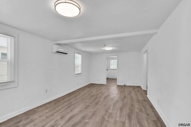 basement featuring an AC wall unit, a wealth of natural light, and light wood-type flooring