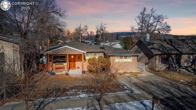 view of front of house featuring roof with shingles, fence, and stucco siding