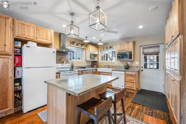 kitchen with dark wood-type flooring, white appliances, a sink, and wall chimney range hood