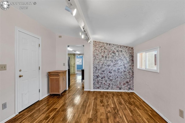 empty room with track lighting and dark hardwood / wood-style flooring