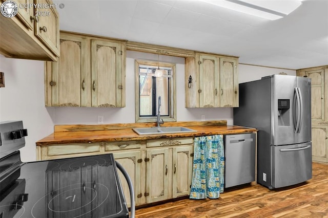 kitchen with stainless steel appliances, sink, wooden counters, and light hardwood / wood-style floors