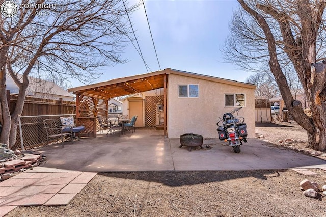 rear view of property featuring a patio and a fire pit