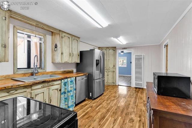 kitchen featuring sink, crown molding, wooden counters, light hardwood / wood-style floors, and black appliances