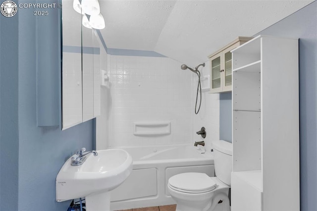 full bathroom featuring toilet, sink, tub / shower combination, vaulted ceiling, and a textured ceiling