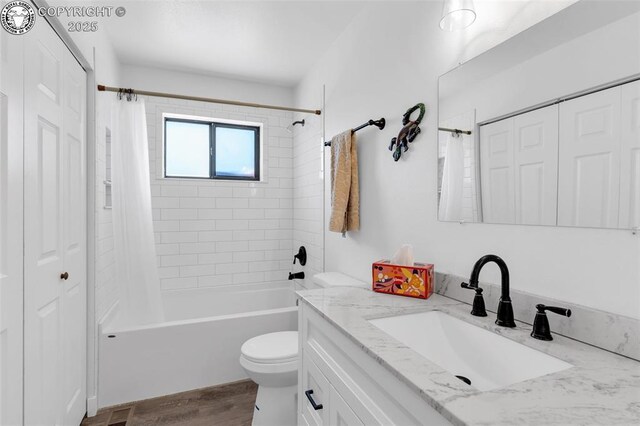 full bathroom with toilet, wood finished floors, shower / bathtub combination with curtain, vanity, and a closet