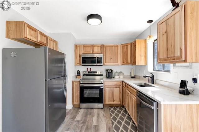 kitchen with stainless steel appliances, light countertops, light wood-type flooring, light brown cabinets, and a sink