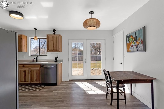 kitchen featuring dark wood finished floors, appliances with stainless steel finishes, brown cabinets, french doors, and a sink