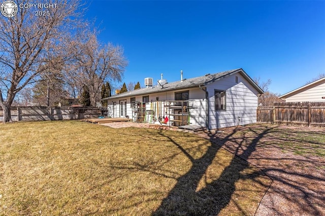 rear view of house featuring a fenced backyard, a lawn, and a wooden deck