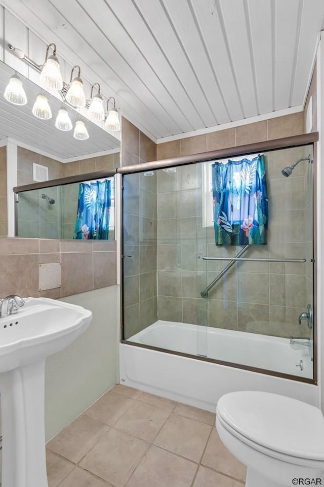 full bathroom featuring sink, tile walls, bath / shower combo with glass door, tile patterned floors, and toilet