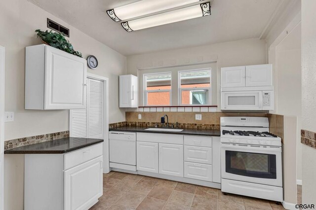 kitchen featuring sink, backsplash, white cabinets, and white appliances